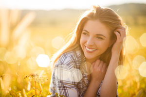 white woman smiling in a sunlit field, general dentistry cinco ranch tx, about lovett dental cinco ranch